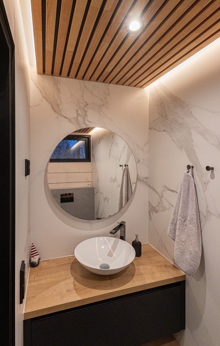 L'illuminazione indiretta a strisce LED in una piccola toilette si riflette magnificamente attraverso le pareti lucide. Con faretto aggiuntivo da 9 watt